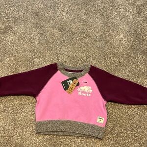 Baby girls pink Roots sweater. Never worn, tags still on. Size 6-12 M.